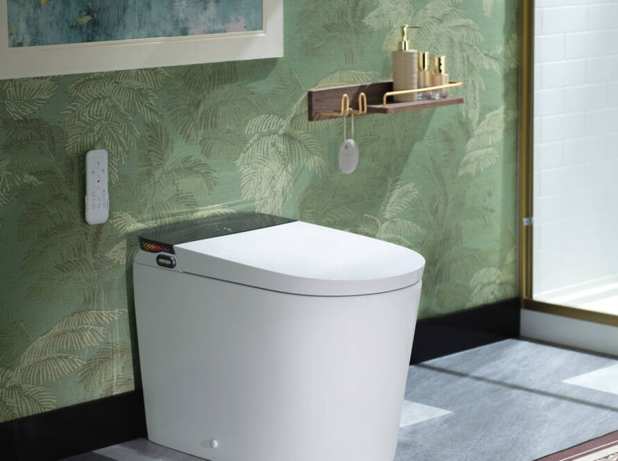 Modern smart toilet installation in a stylish bathroom with green foliage wallpaper, featuring a remote control and elegant accessories.