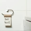 Toilet paper roll holder with a note saying "Don't Panic!" in a modern bathroom setting, emphasizing comfort and smart upgrades in bathroom design.