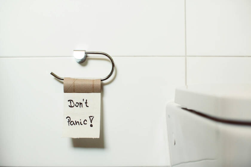 Don't Panic! note hanging on a toilet paper holder next to a smart toilet, emphasizing comfort and convenience in modern bathroom design.