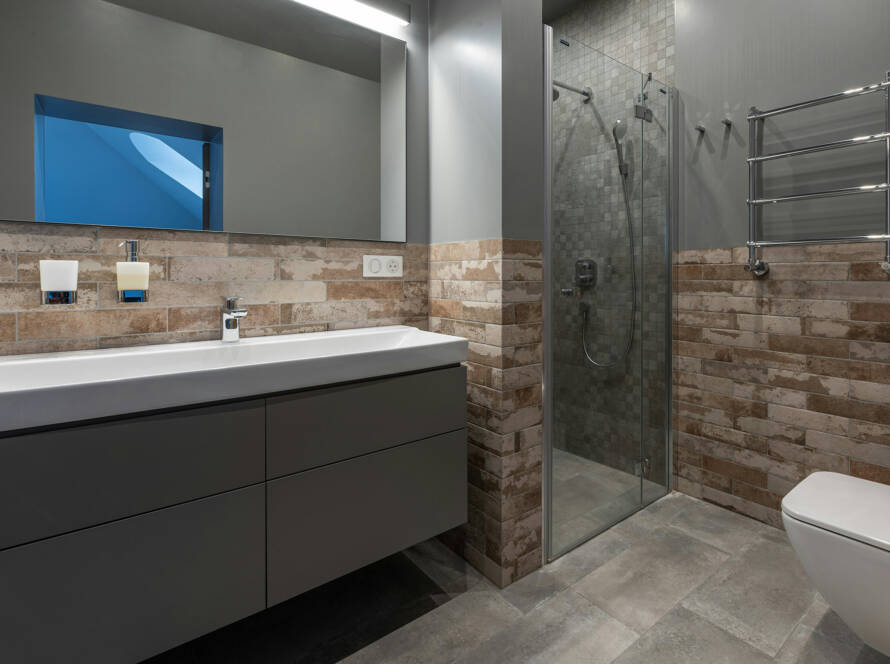 Modern bathroom design featuring a sleek gray vanity with a white sink, stylish wall-mounted faucets, and a glass shower enclosure, emphasizing luxury and efficiency in home upgrades.