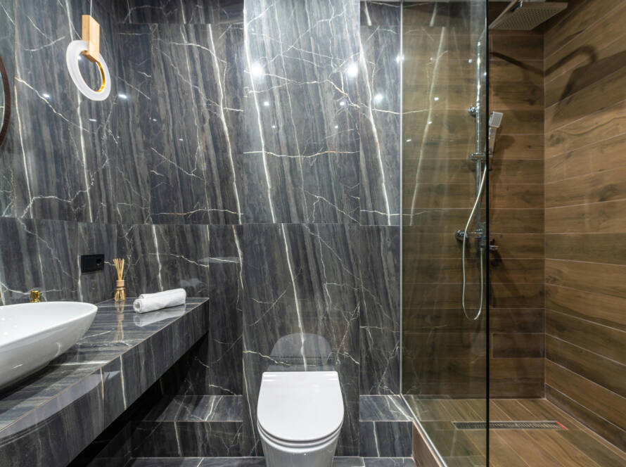 Modern bathroom featuring a sleek white smart toilet, elegant marble walls, and a glass shower enclosure, emphasizing luxury and comfort in home upgrades.