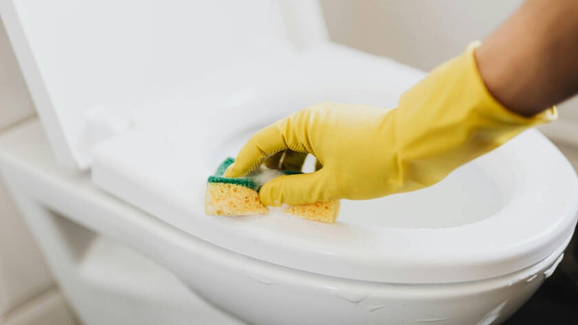 Person cleaning a smart toilet with a sponge, highlighting maintenance tips for modern bathroom technology.