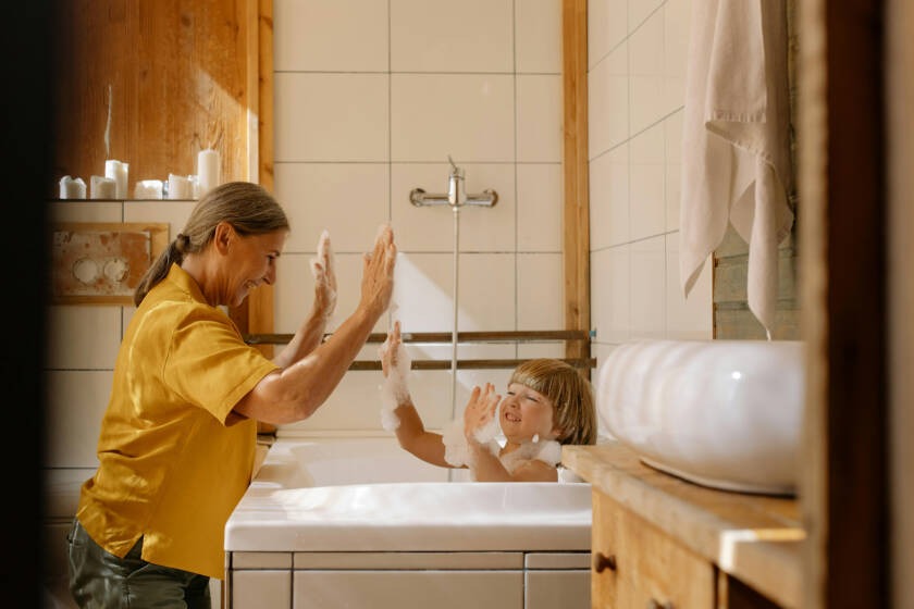 Woman and child playing in a modern bathroom during a bath, showcasing a family-friendly environment ideal for smart toilet installations and upgrades.