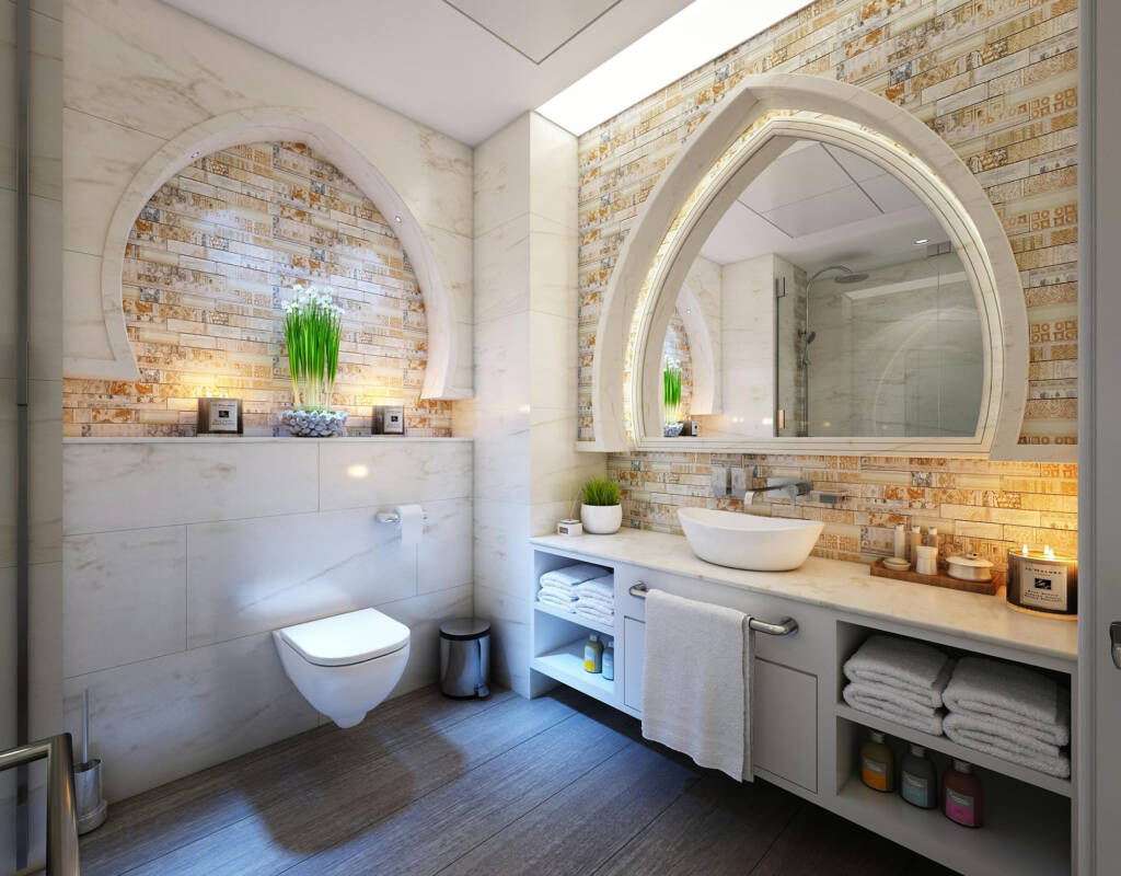 Modern bathroom featuring a smart toilet, elegant stone wall design, stylish arched mirror, and well-organized vanity with towels and decor, emphasizing the quality of smart toilet installations by trusted professionals.